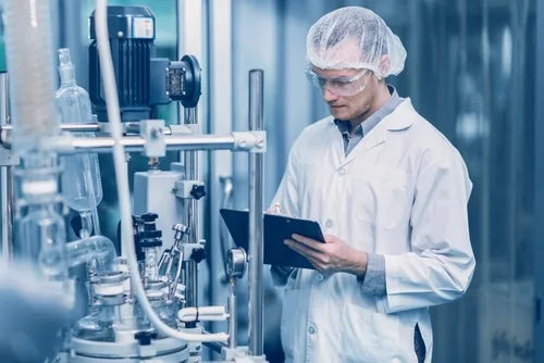 Mitarbeiter mit Schutzkleidung und Tablet an einer Produktionsanlage